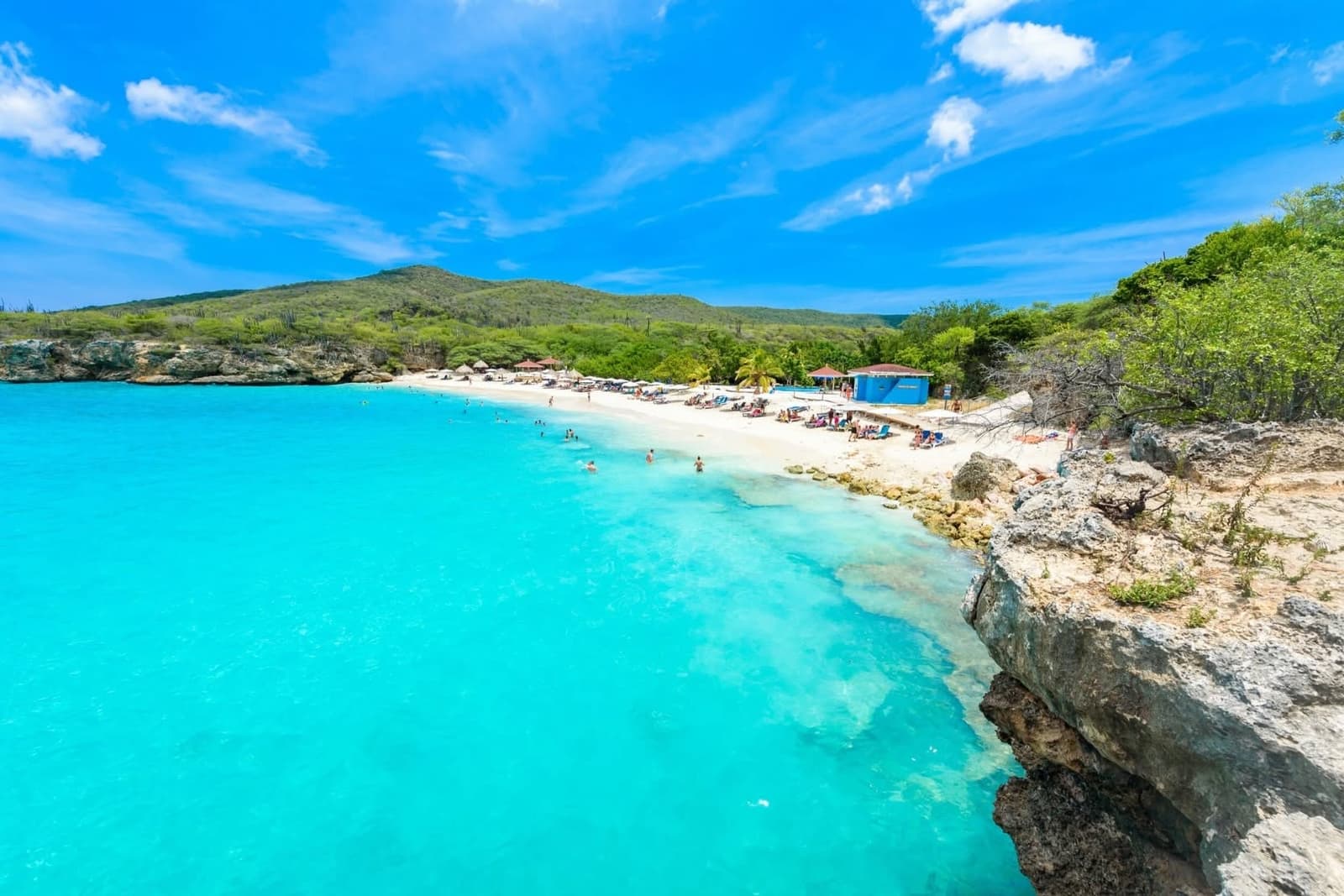 Turquoise-water beach at Sandals Royal Curacao with limestone cliffs and palms